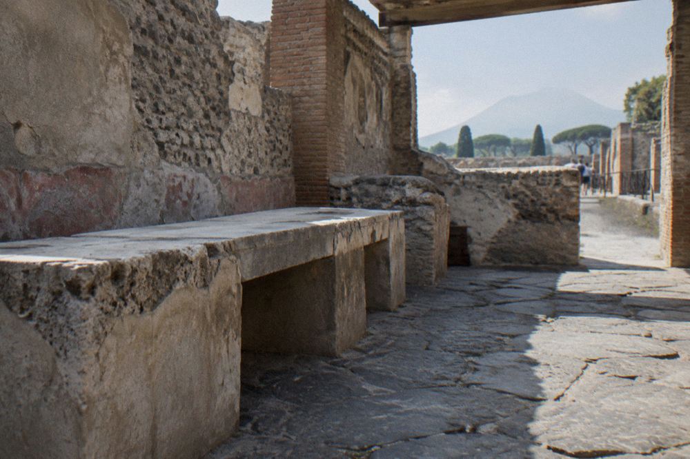 Small group of visitors listening to a guide beside ruined Roman walls in Pompeii
