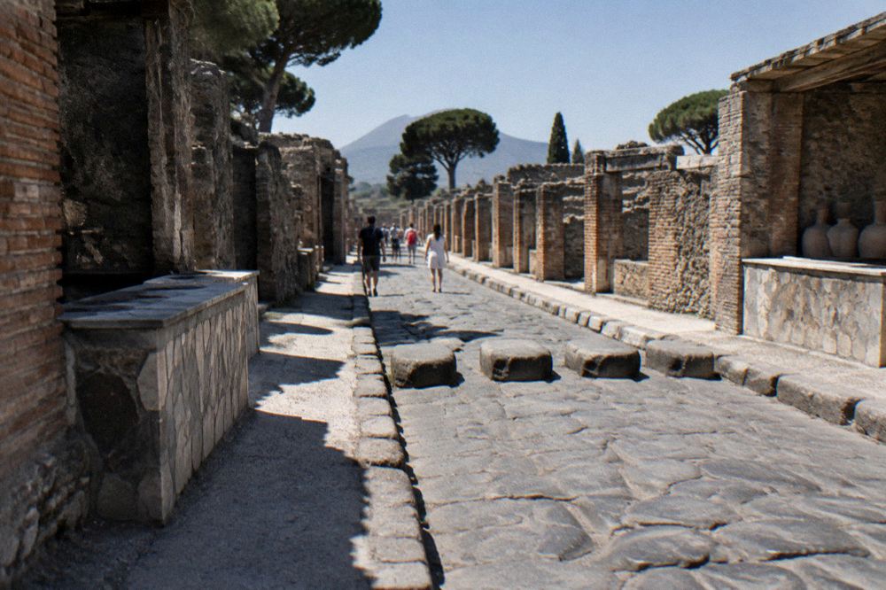 Roman stepping stones crossing an ancient paved street beside a stone fountain in Pompeii