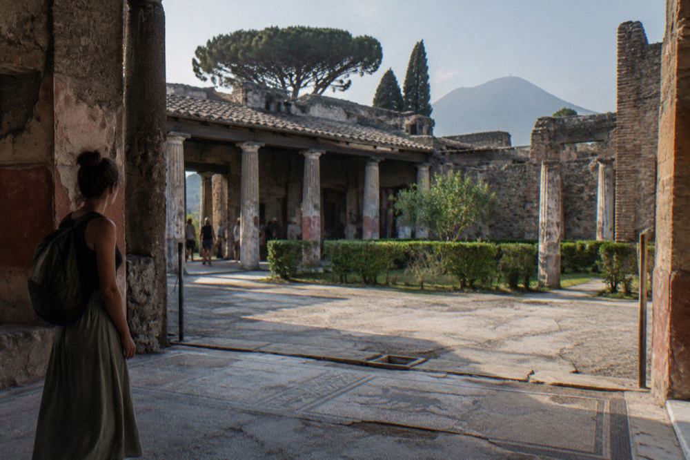 Stone columns and doorways of a large ancient Roman house in Pompeii under a clear sky