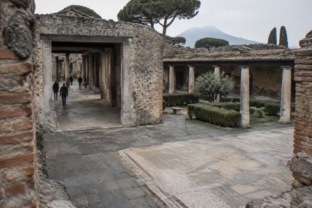 Ancient stone street with wheel-worn paving stones running between ruined walls in Pompeii