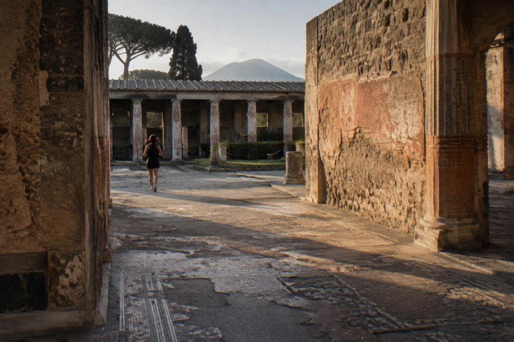 Worn stone paving and low curbs of a narrow ancient street lined with ruined brick walls