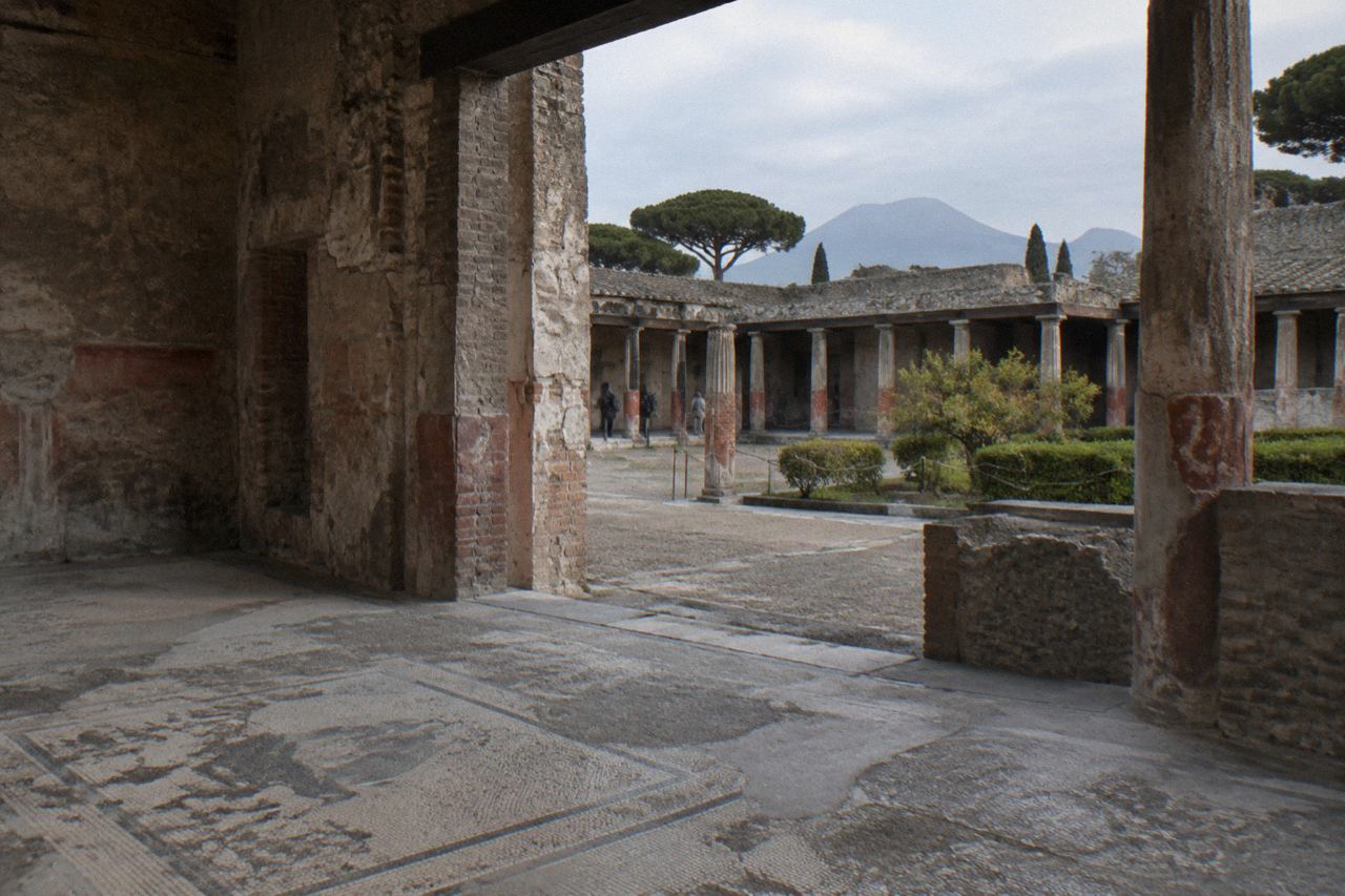 Stone columns and doorways of a large ancient Roman house in Pompeii under a clear sky