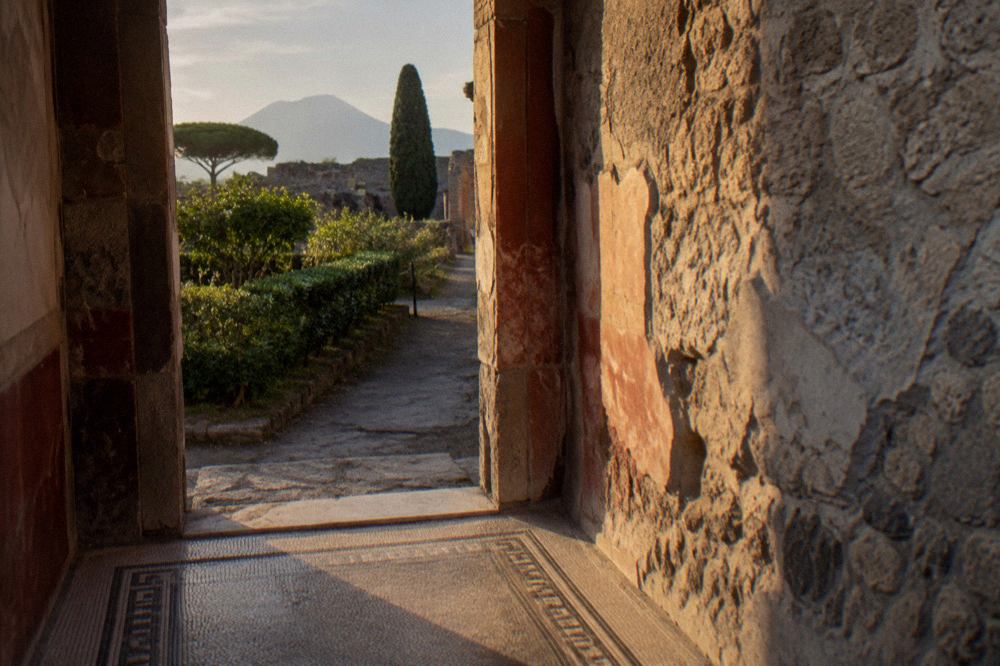 Ancient stone doorway and painted wall of a Roman house in Pompeii under a bright sky