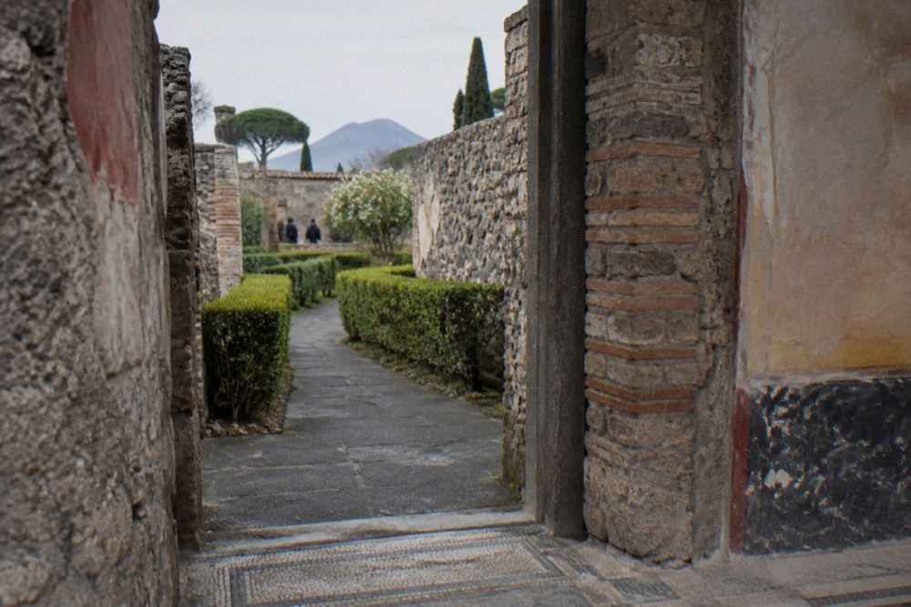 Group of visitors listening to a guide beside ancient Roman walls in Pompeii