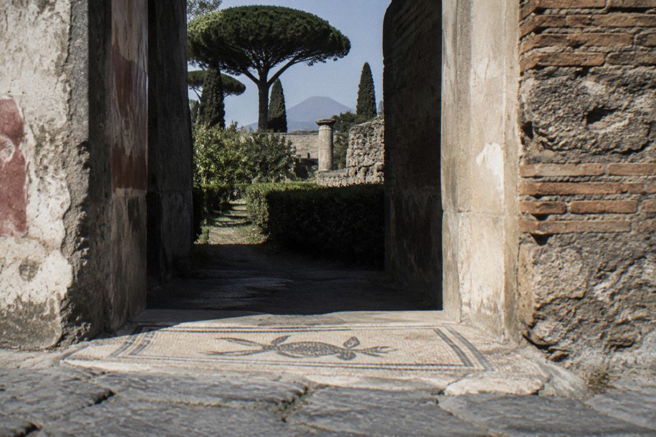 Ancient stone doorway and painted wall of a Roman house in Pompeii under a bright sky