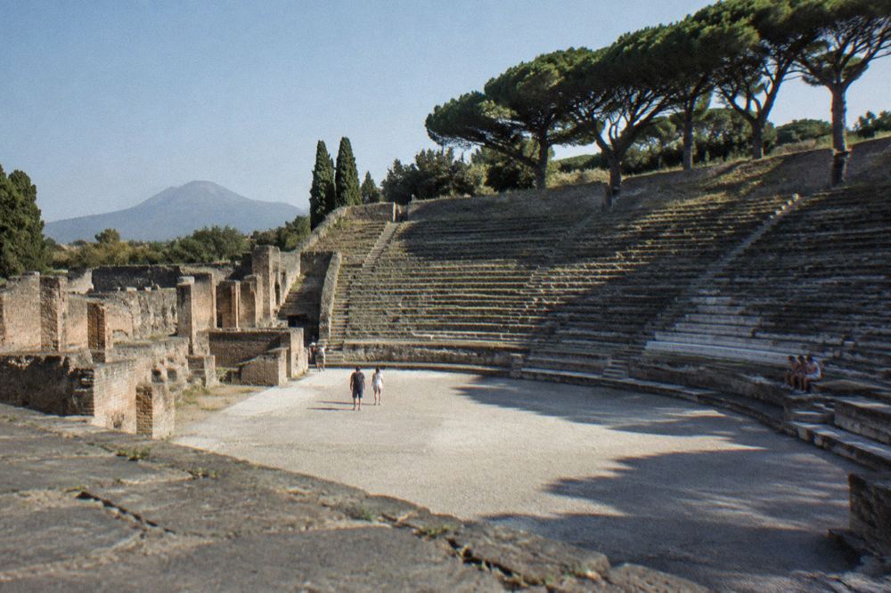 Wide view across the excavated ancient city of Pompeii with ruined walls and Mount Vesuvius behind