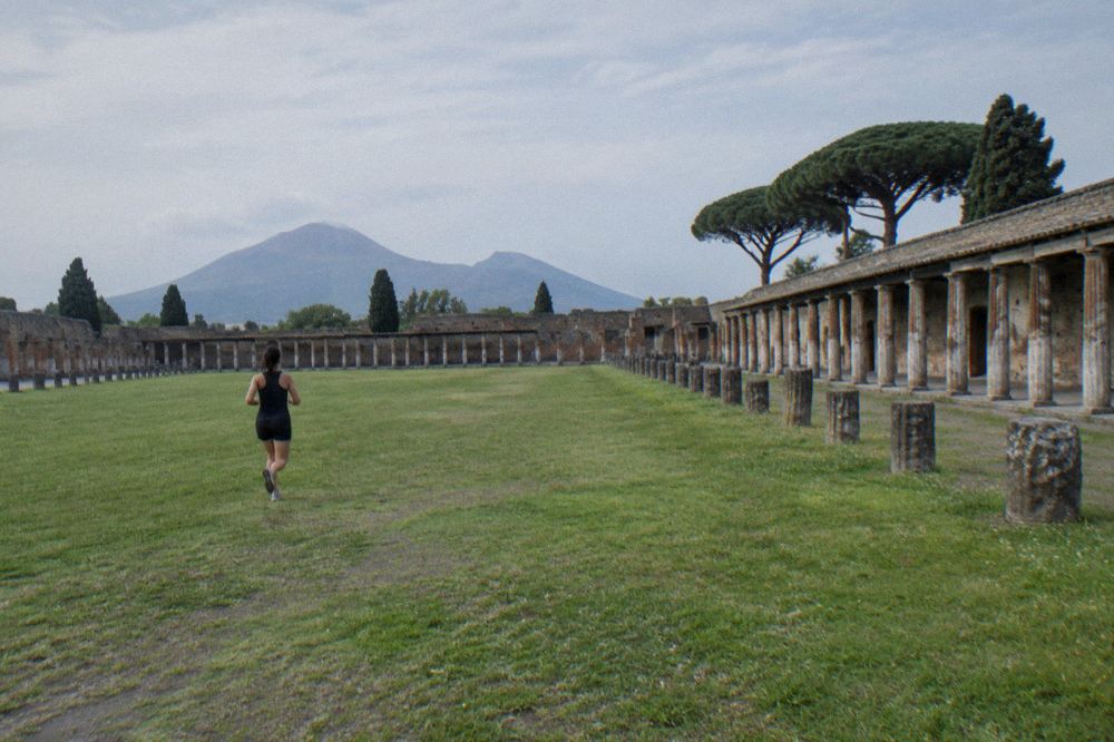 An ancient stone-paved open court with columns under a clear blue sky and scattered autumn leaves