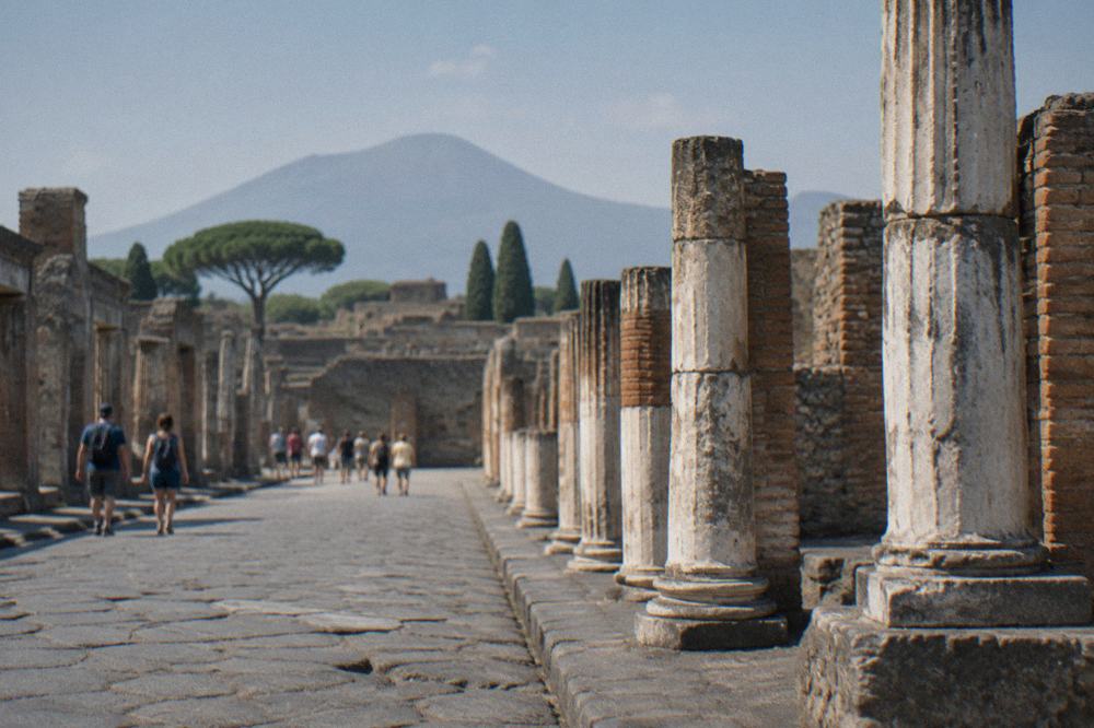 Ancient stone-paved street in Pompeii under bright midday sun with worn cart ruts