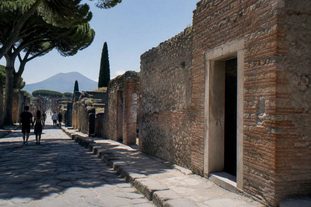 Guide pointing at a faded ancient wall while a small group listens in a narrow stone corridor