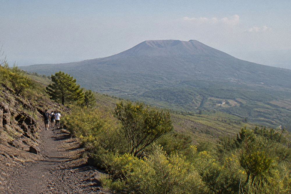 The crater rim of Mount Vesuvius under a clear sky with the Bay of Naples in the distance
