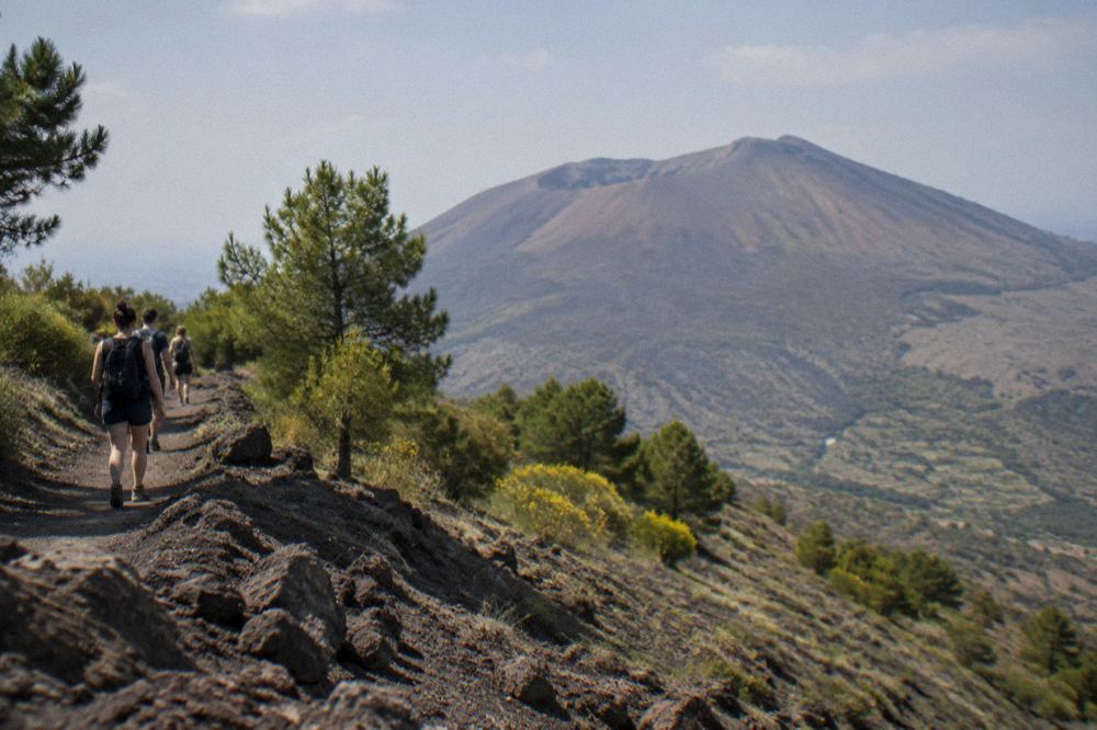 The rim path of Vesuvius with steam vents and dark rock inside the crater