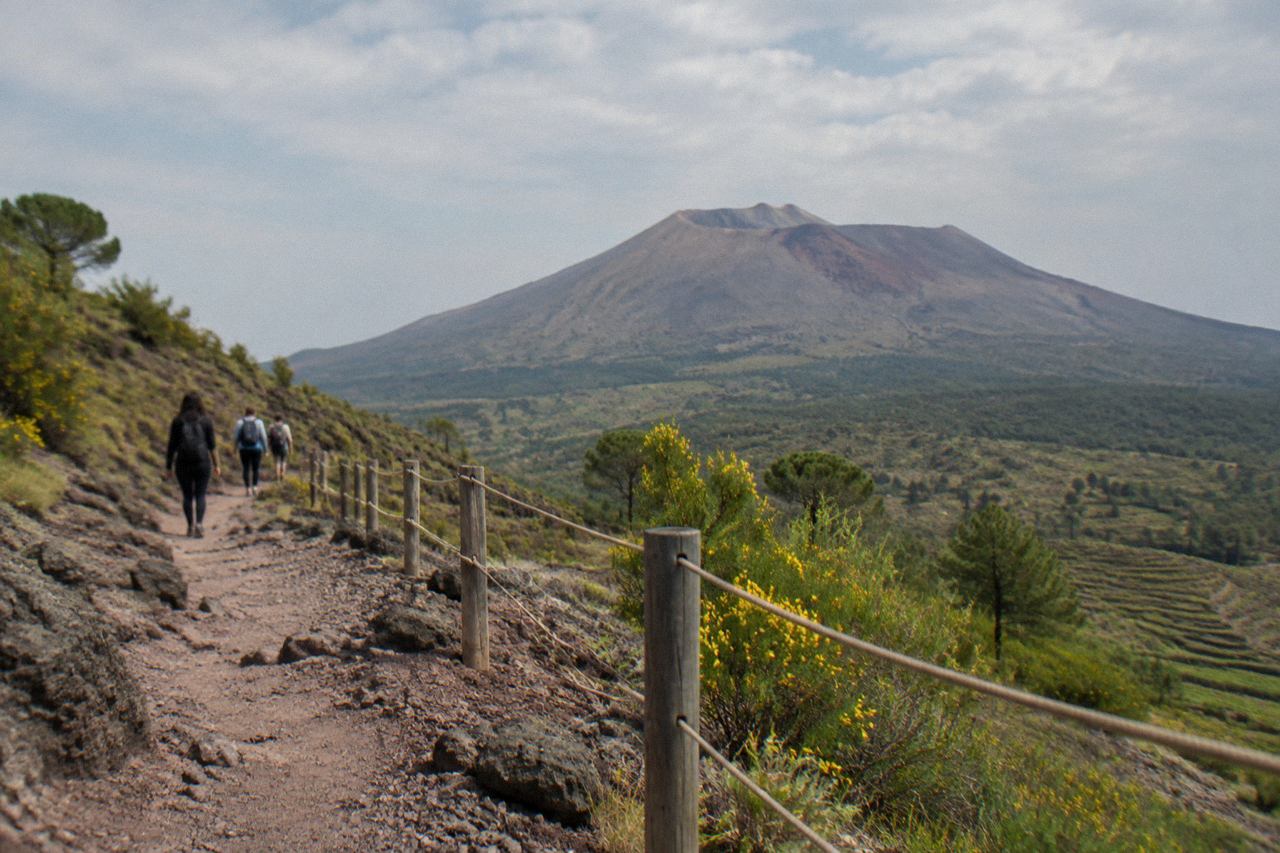 The crater rim of Mount Vesuvius under a clear sky with the Bay of Naples in the distance