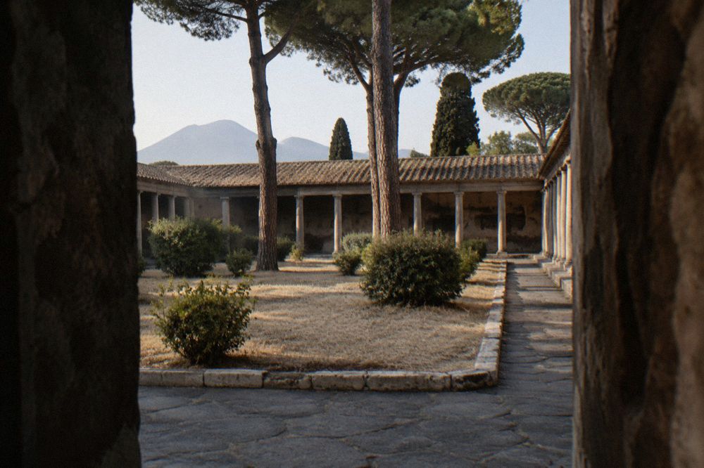 Late afternoon sunlight across the stone tiers of the Pompeii arena with long shadows