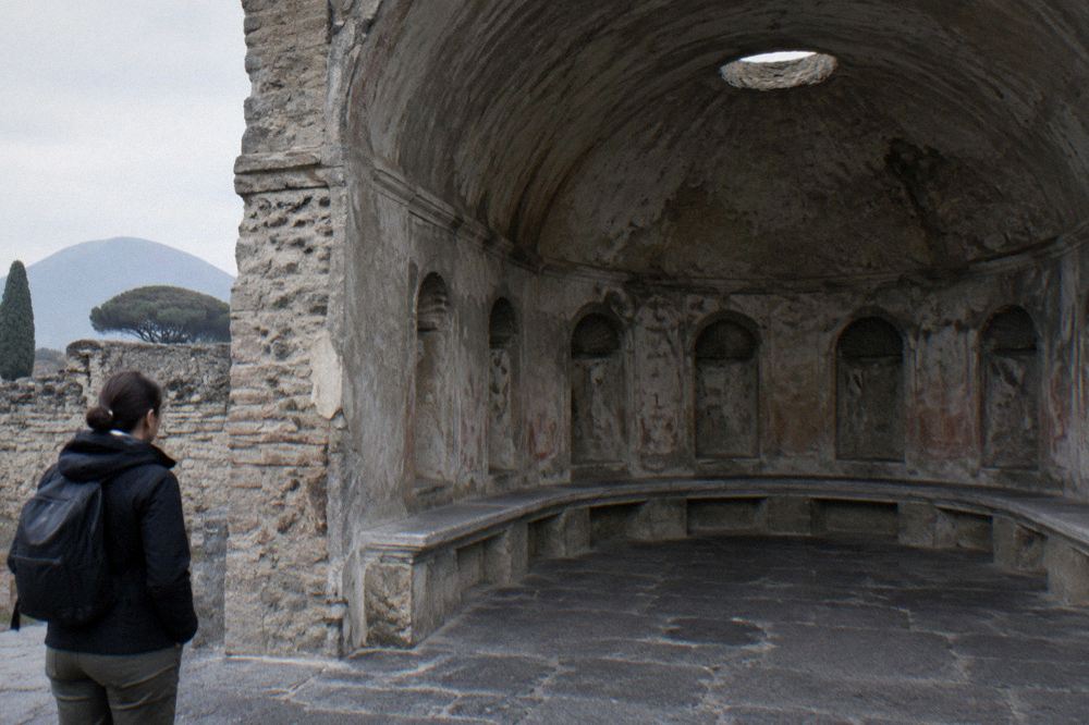 Museum corridor lined with ancient sculptures and display pedestals