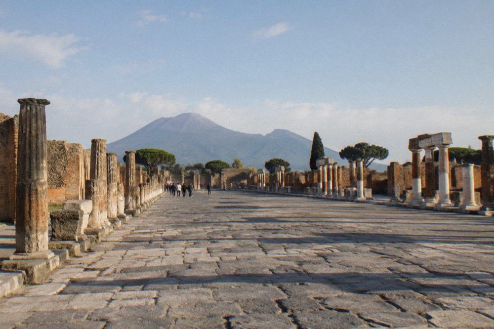 Ancient paved road with worn stepping stones leading toward a city gate of Pompeii
