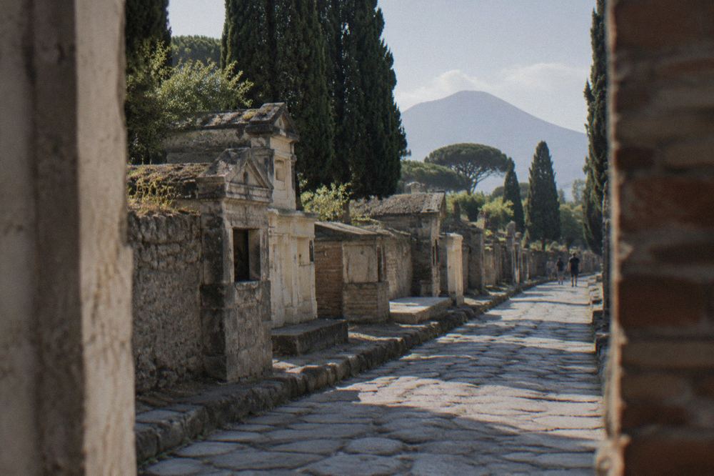 Ancient Roman city gate with stone archway opening onto a street of tombs