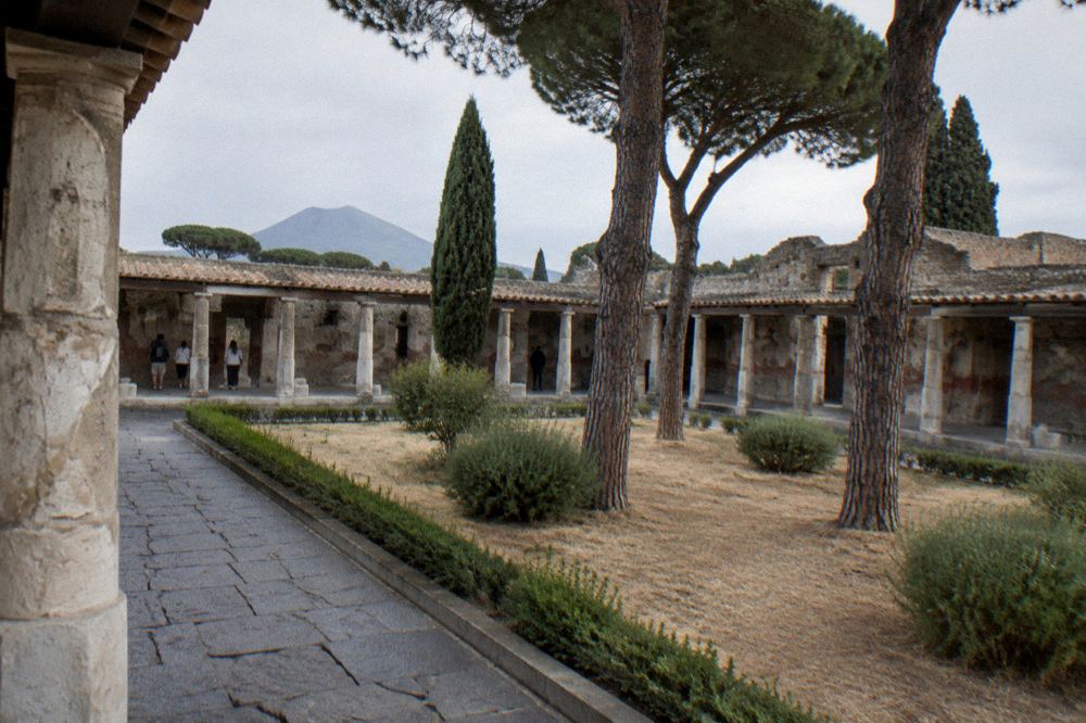 View along the ancient city wall of Pompeii with tomb monuments visible beyond the gate