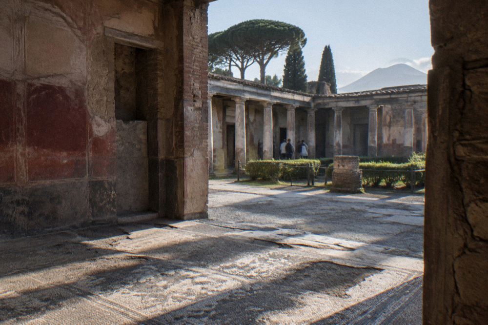Visitors walking the wide ancient street inside Pompeii near the entrance gate