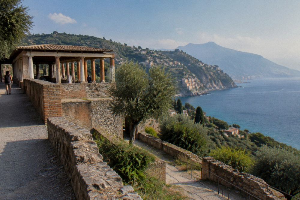 Railway line running along the shore beneath a cliffside Italian town