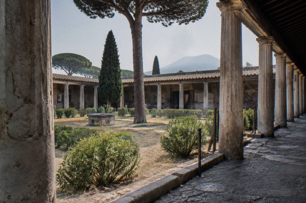 A raised stone temple platform with column bases seen across an ancient paved square