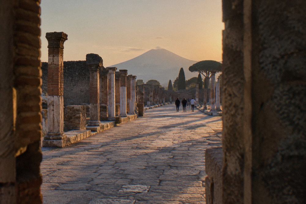 A row of ancient columns casting long shadows across stone paving in warm afternoon light