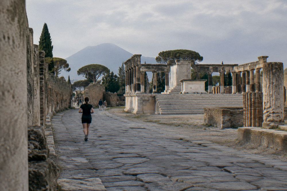 Visitors' shadows stretching across ancient pavement as the sun lowers behind ruined walls