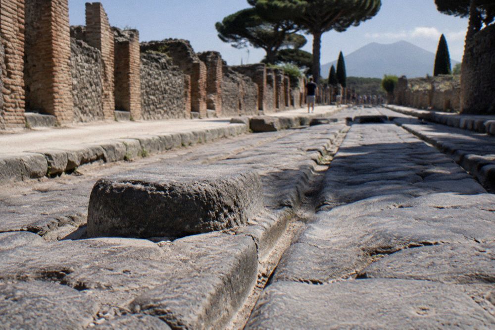 Group of visitors walking with a guide along a ruined Roman street lined with old walls