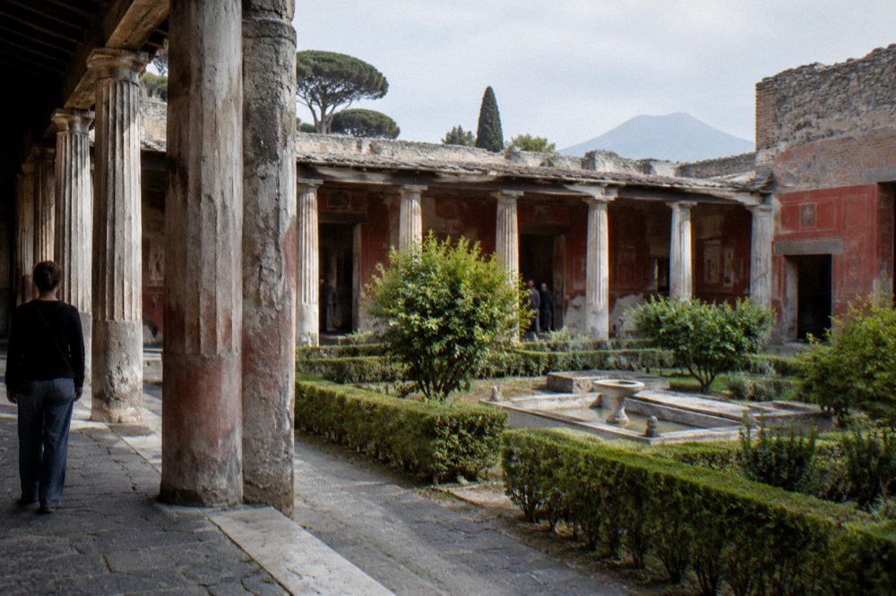 Wide view of excavated Roman ruins with Mount Vesuvius rising in the background