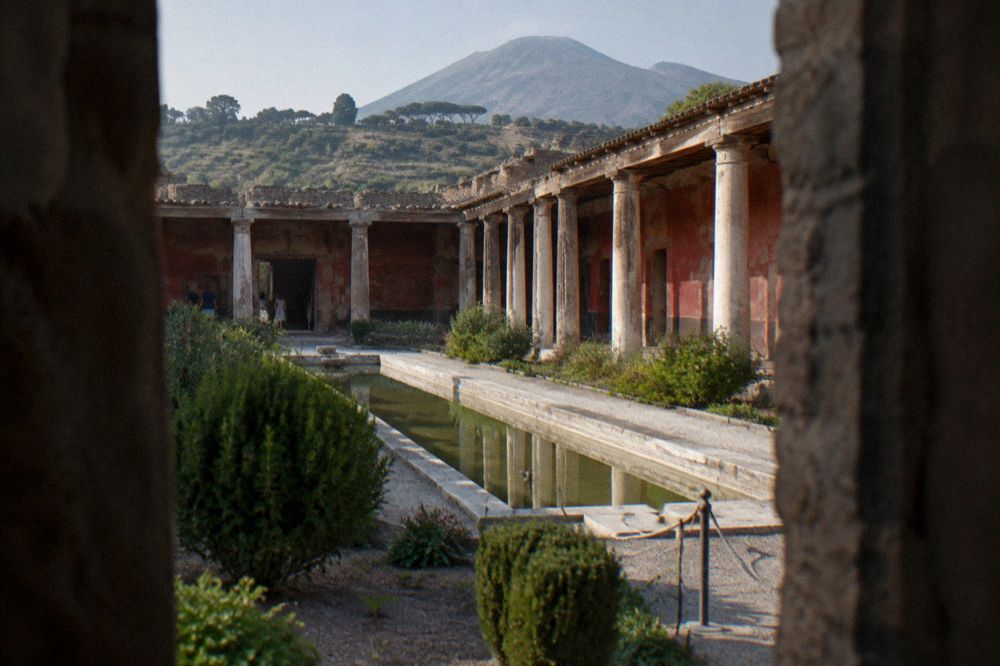 Interior of a Roman villa room with tall painted walls and low doorways opening to daylight