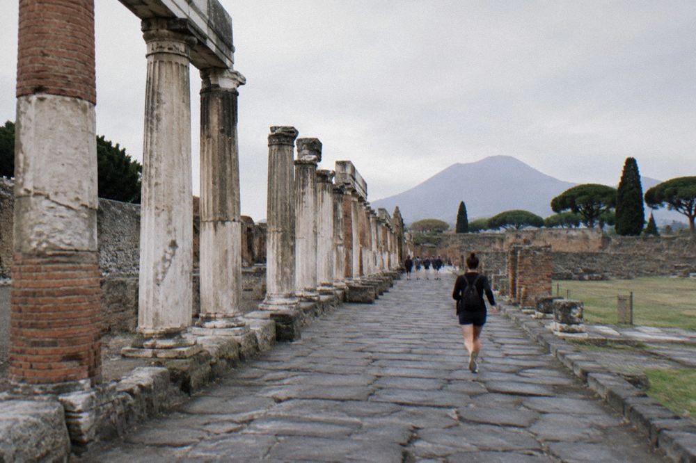 Wide view of an excavated Roman villa terrace with stone columns and distant coastline