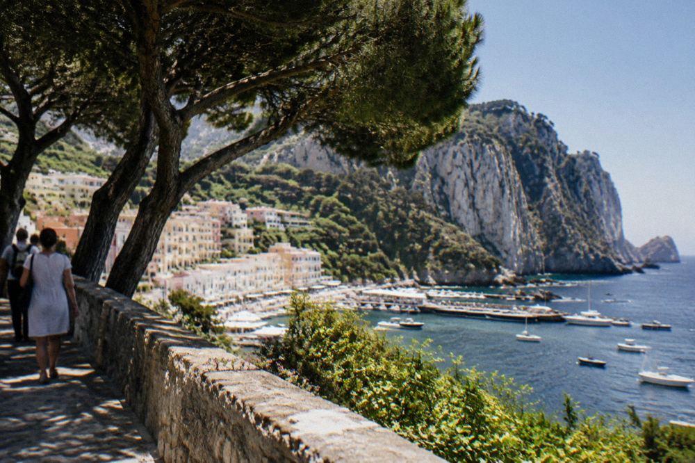 A guided group walking between ancient stone walls in bright sun