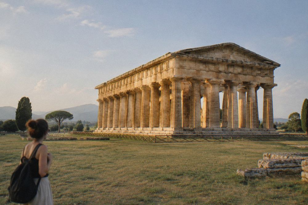 Roman stone columns and ruined walls under bright midday sun with few people about