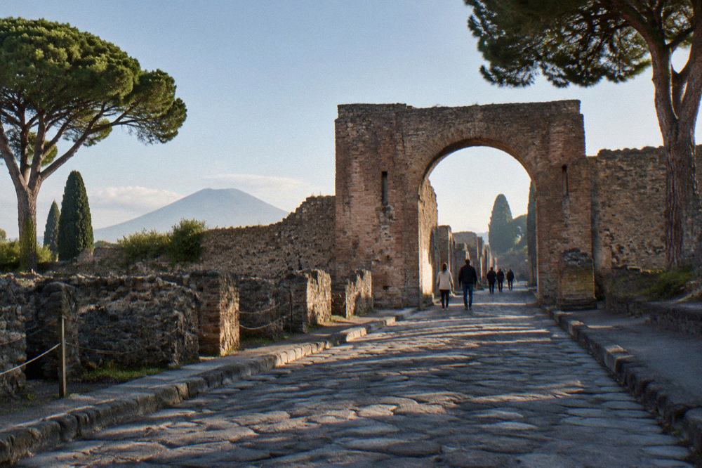 Sunlit stone street of the excavated Roman city with Mount Vesuvius rising in the background
