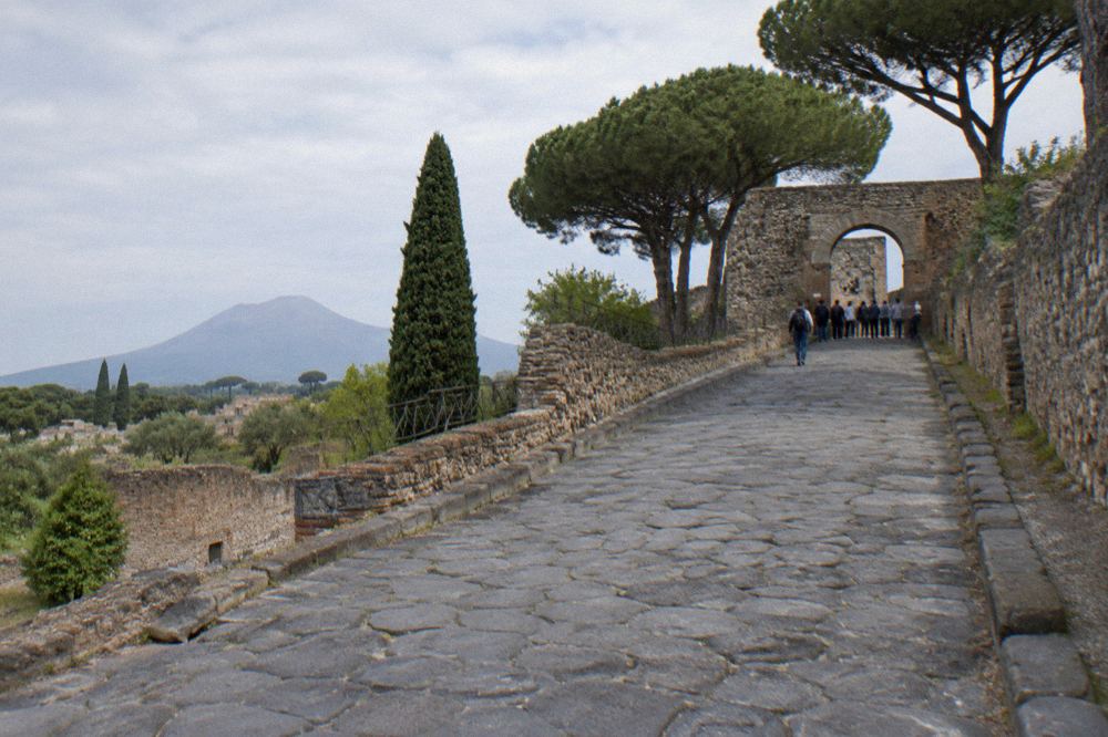 The stone gateway of an ancient Roman city entrance with an archaeological park sign beside it