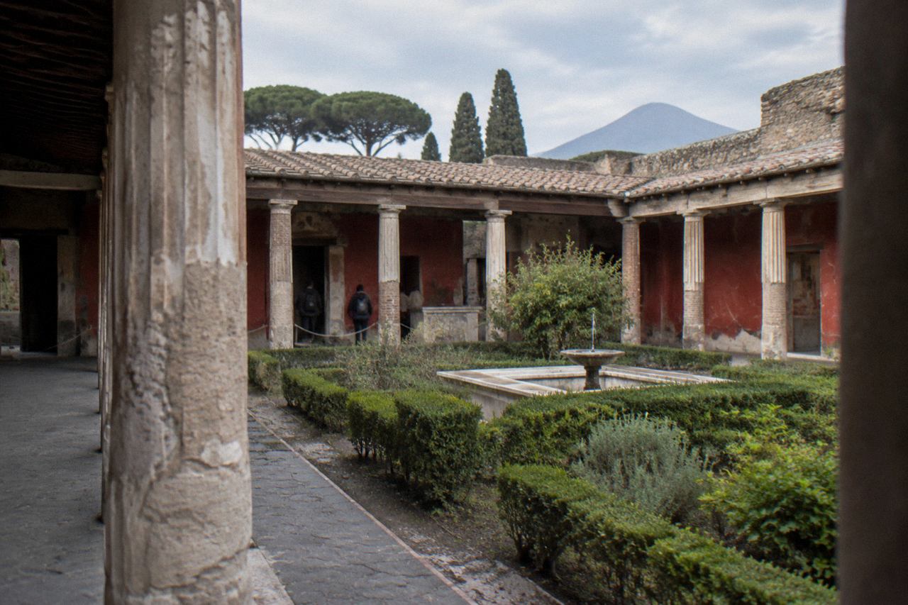 Stone street of ancient Pompeii with worn wheel ruts and broken columns under a clear sky
