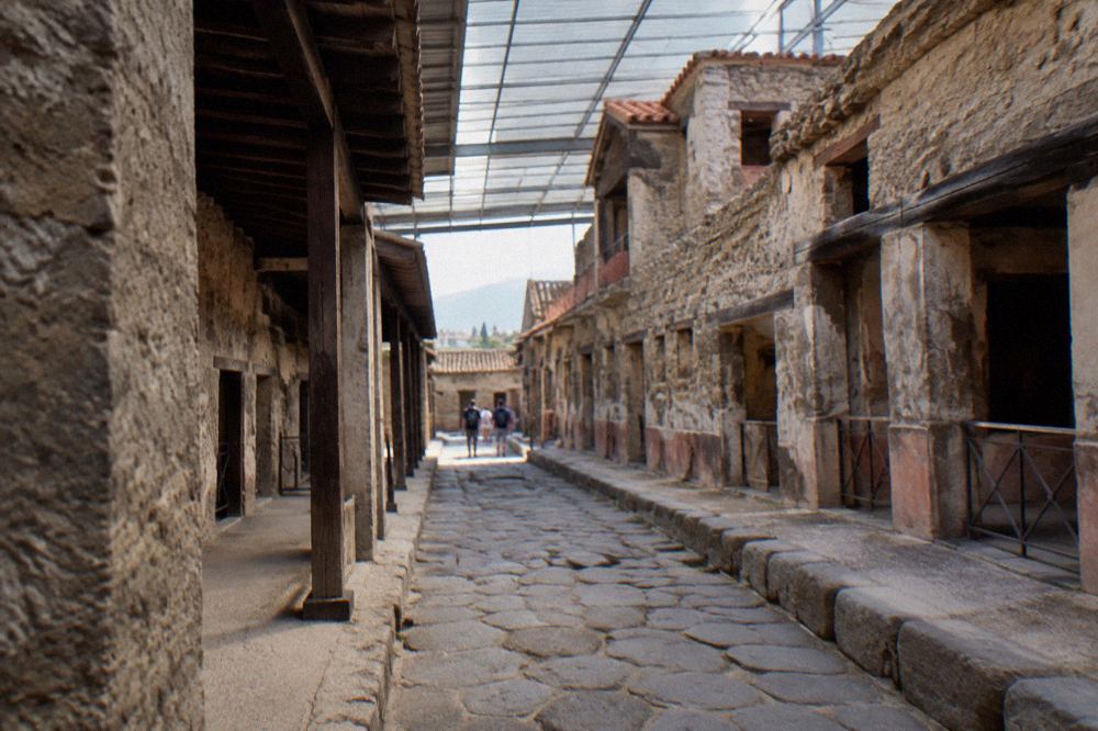 The excavated terrace of the ancient Roman site of Herculaneum under a clear sky with Mount Vesuvius in the background