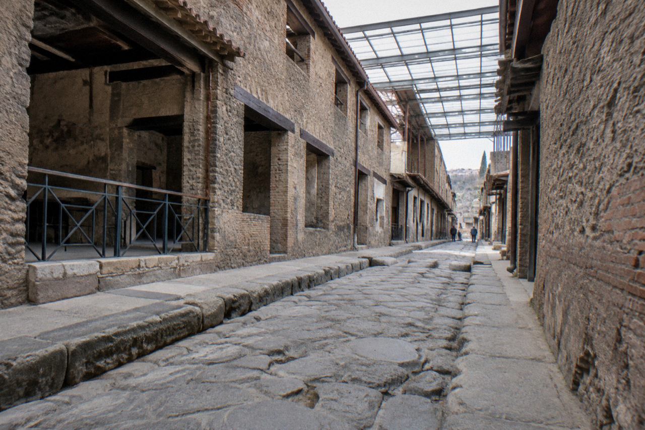 The excavated terrace of the ancient Roman site of Herculaneum under a clear sky with Mount Vesuvius in the background