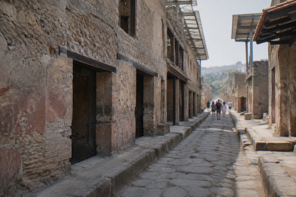 A glass-walled shelter enclosing ancient skeletal remains inside a stone vaulted boat shed at Herculaneum