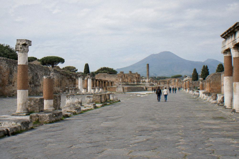 Visitors walking through an ancient stone gateway at Pompeii