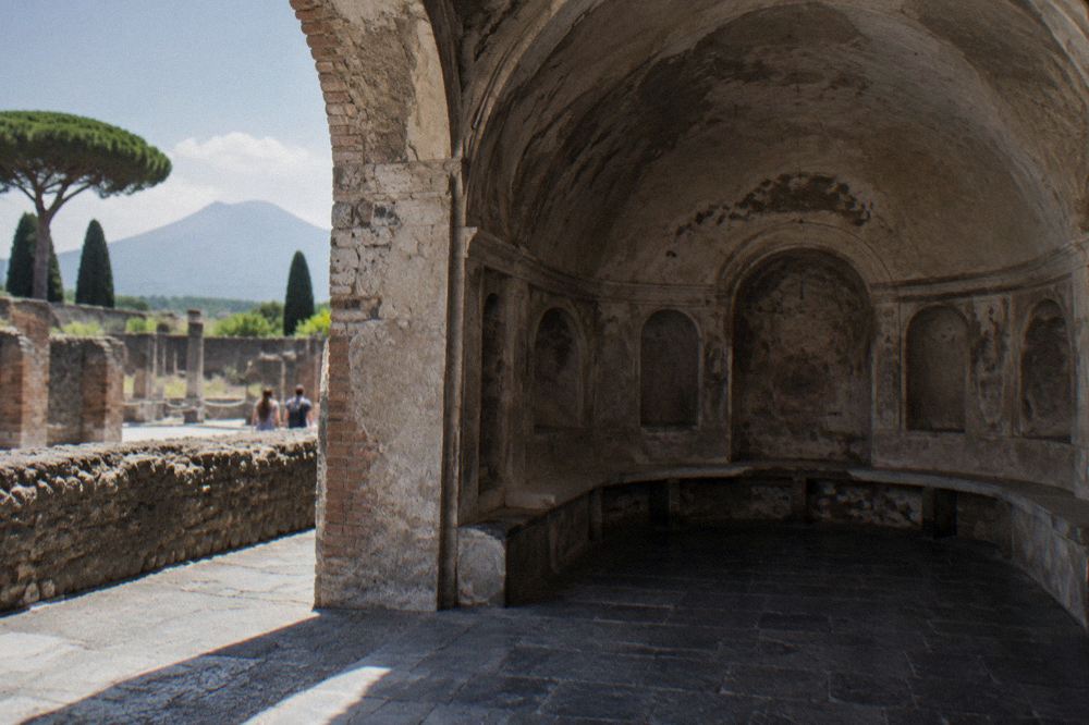 Wide ancient paved street in Pompeii lined with stone walls and wheel-rutted paving