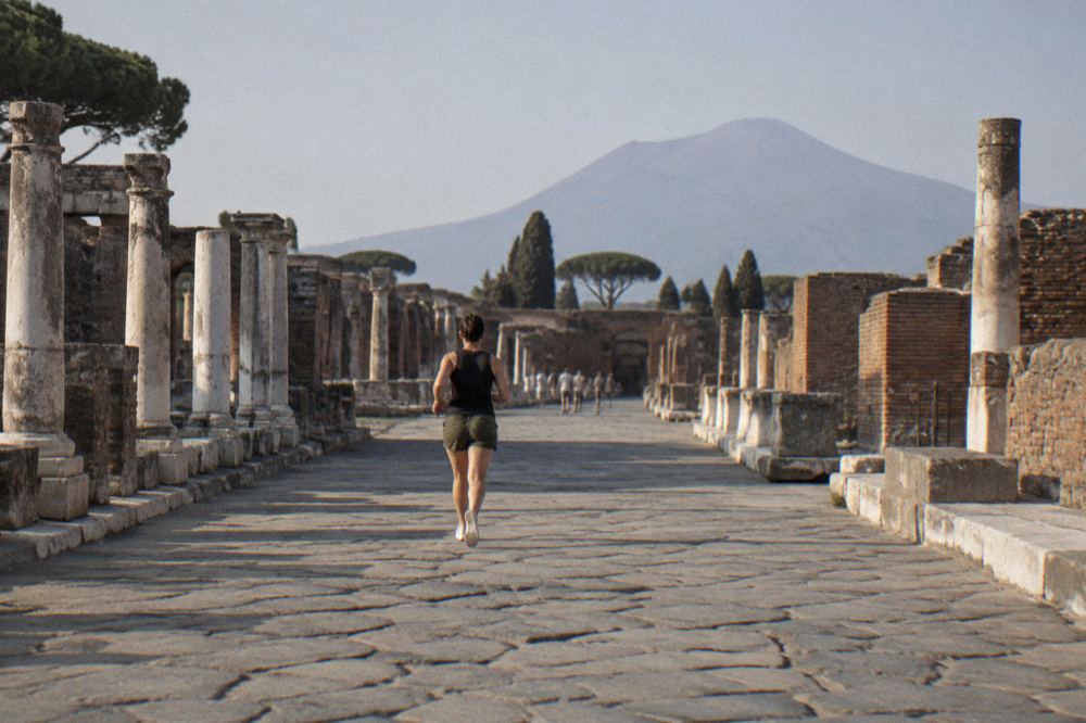Ruined columned building in Pompeii with Mount Vesuvius rising in the background