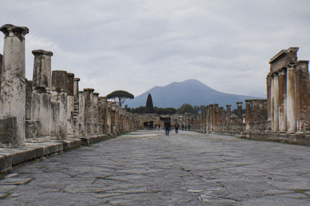Group of visitors listening to a guide beside ruined Pompeii walls in morning light