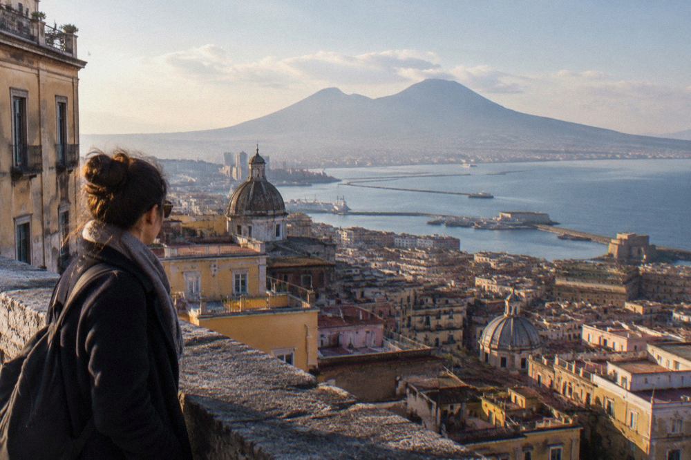 The stone street and ruined walls of Pompeii under a wide sky with Vesuvius on the horizon