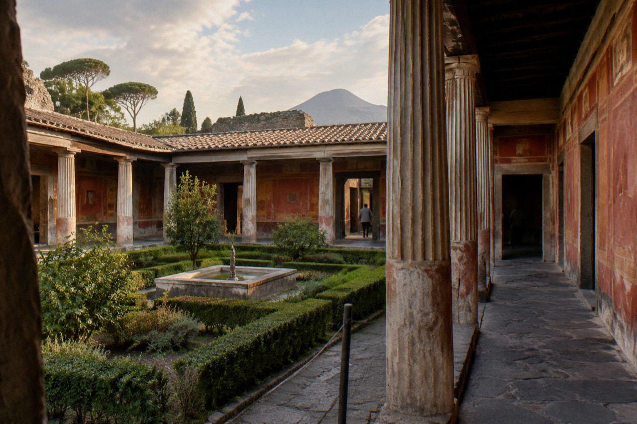 A wide ancient stone-paved street in Pompeii lined with ruined walls under a bright sky