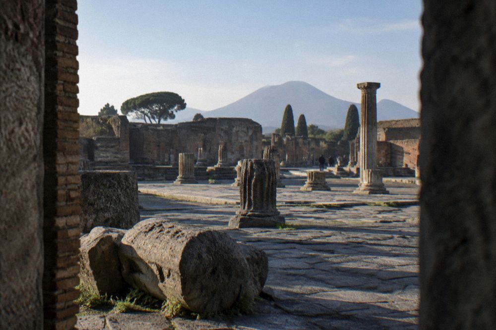 Sunlit stone-paved lane in Pompeii bordered by low ruined walls in warm afternoon light