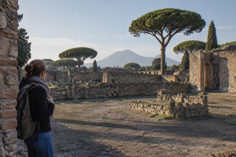 The excavated street frontage of Pompeii under open sky with Mount Vesuvius on the horizon