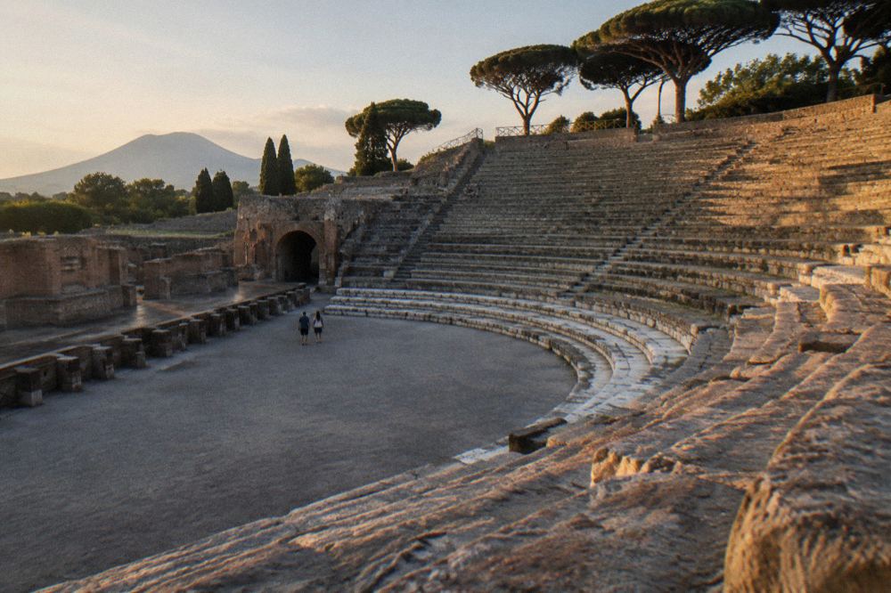 An ancient paved Roman street with stepping stones and worn ruts under strong sunlight