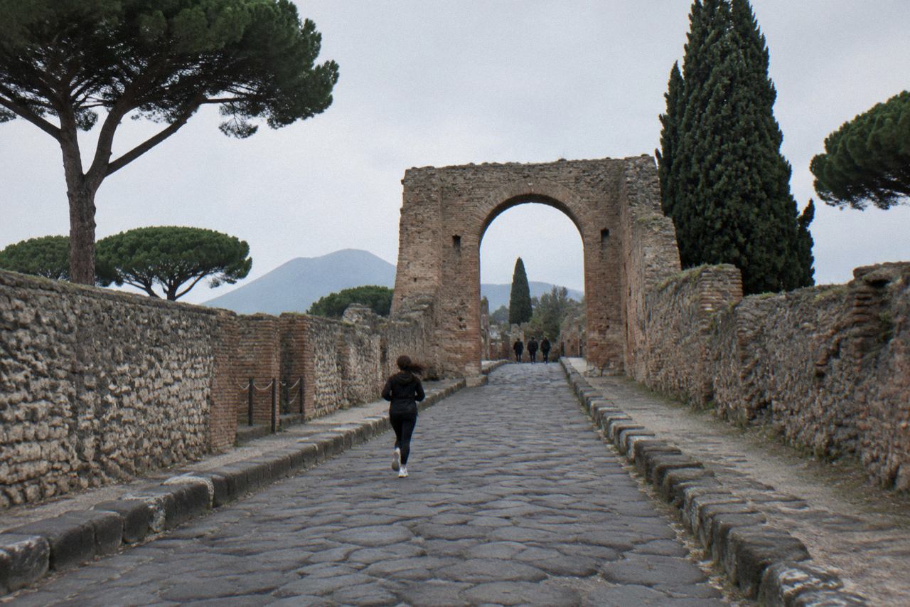Ancient stone gateway of Pompeii with worn stepping stones and ruined walls under a clear sky