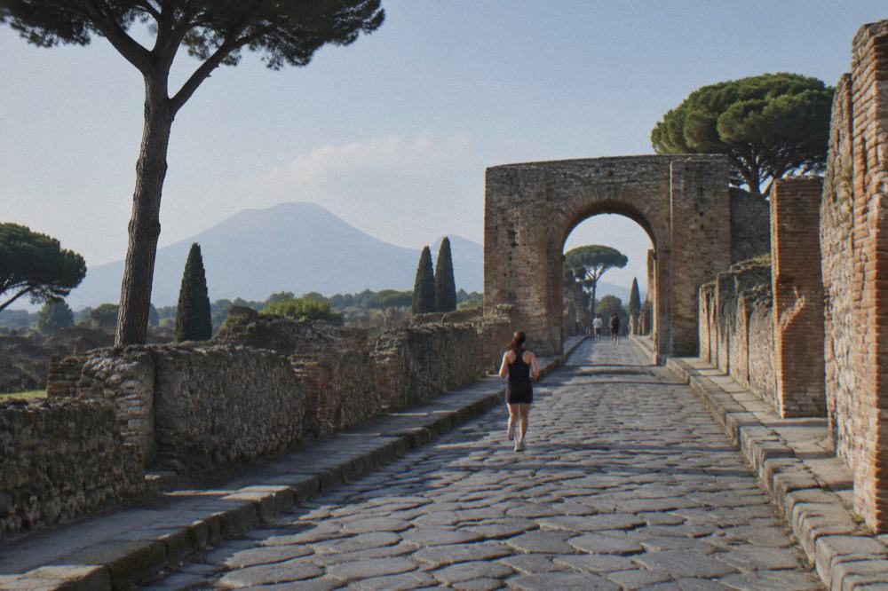 Crowded stone avenue inside Pompeii with visitors walking between ancient walls in morning light