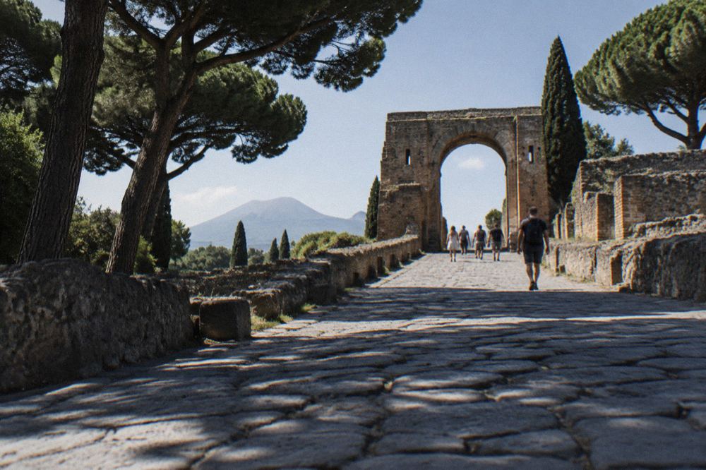 Wide view of the Pompeii forum with Mount Vesuvius rising behind the ruined colonnades